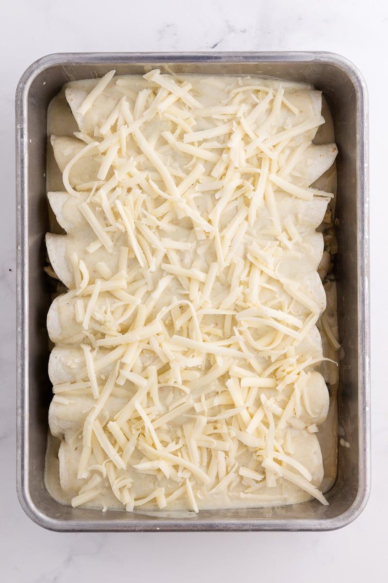 Cheese is sprinkled on top of the enchiladas.