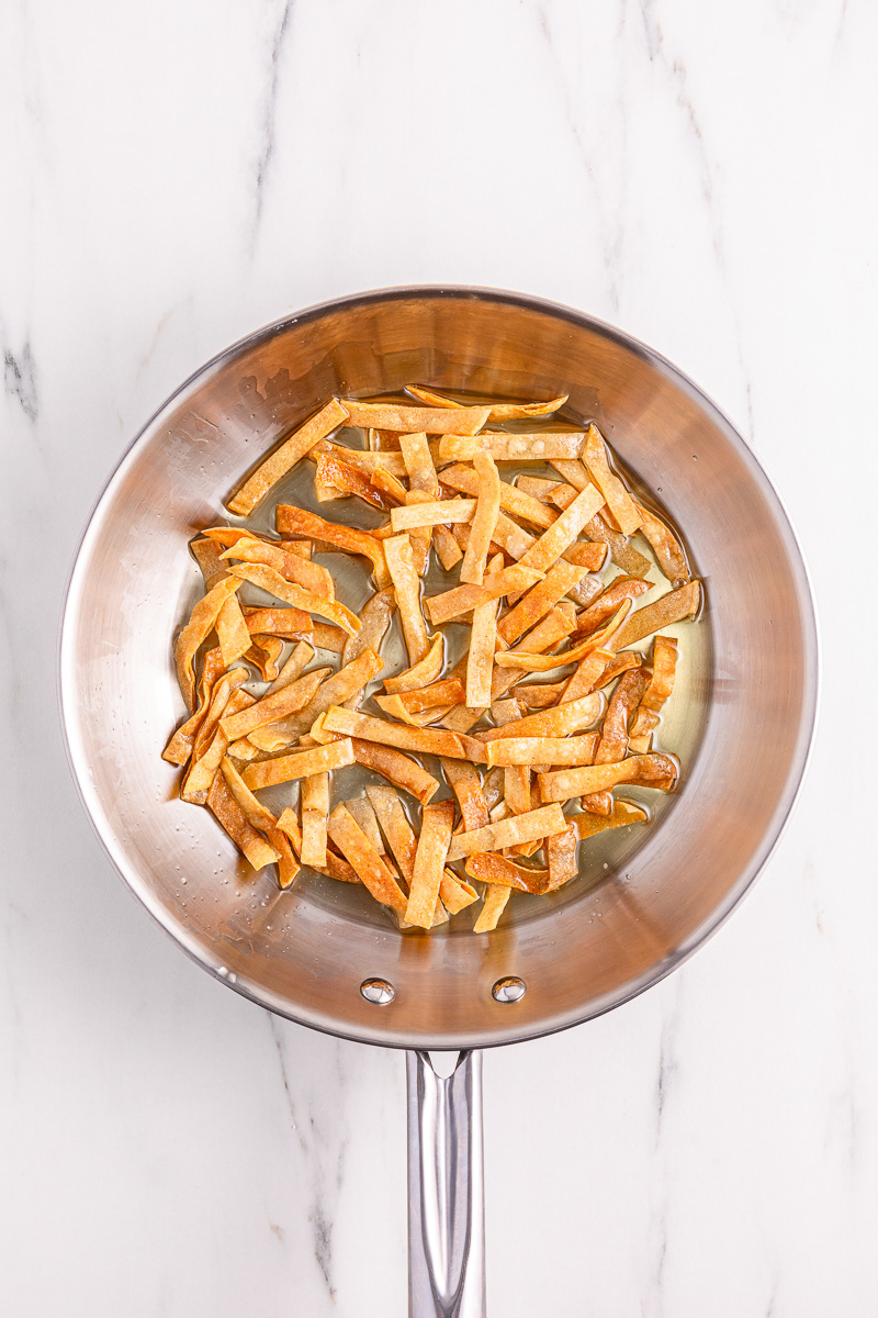 Tortilla strips cooking in oil.