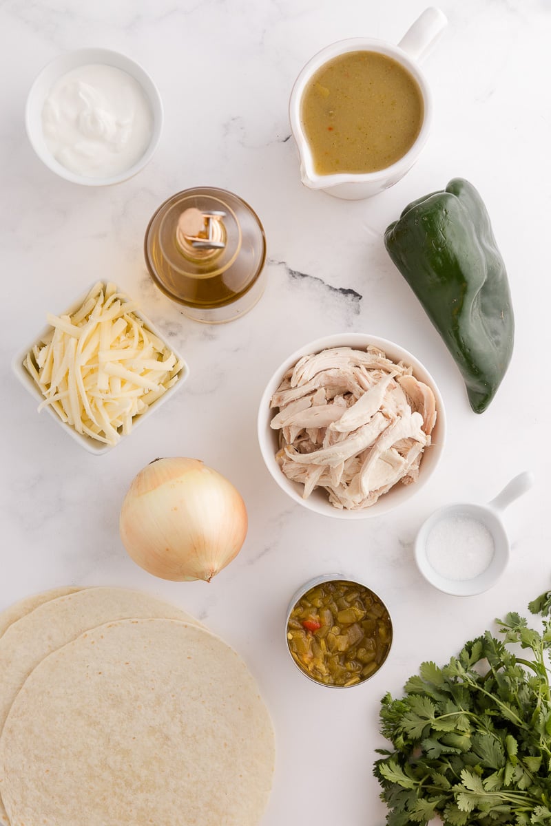 Sour cream green chili enchiladas ingredients in small bowls on counter.