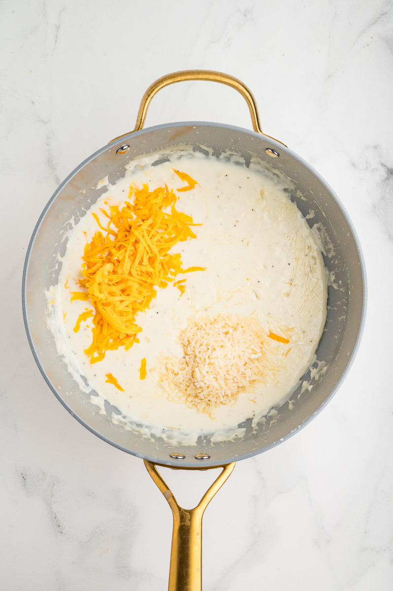 Cheddar and parmesan cheeses are added to skillet.