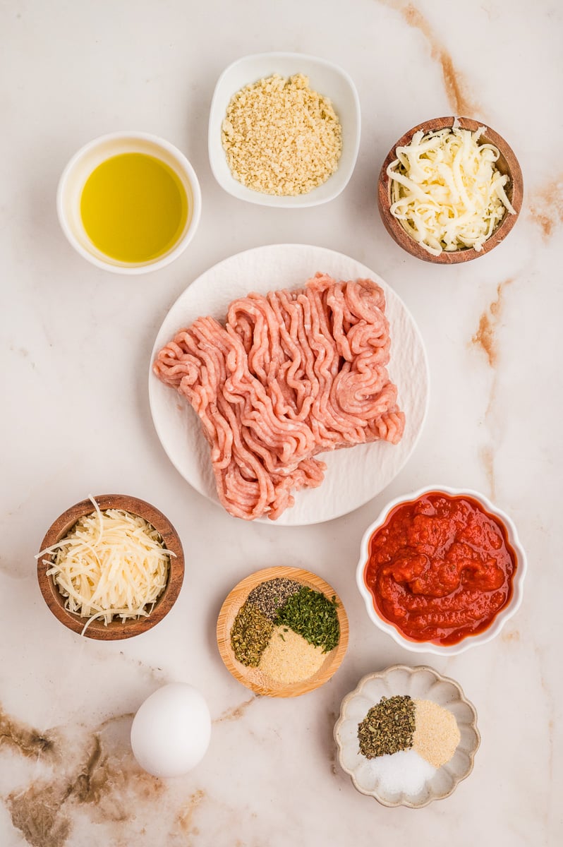 Ingredients for chicken parmesan meatballs in small bowls on counter.