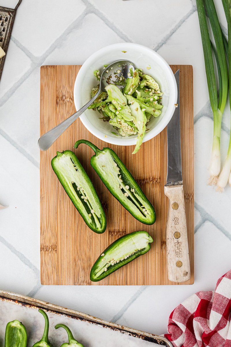 Sliced jalapenos on a wooden board.