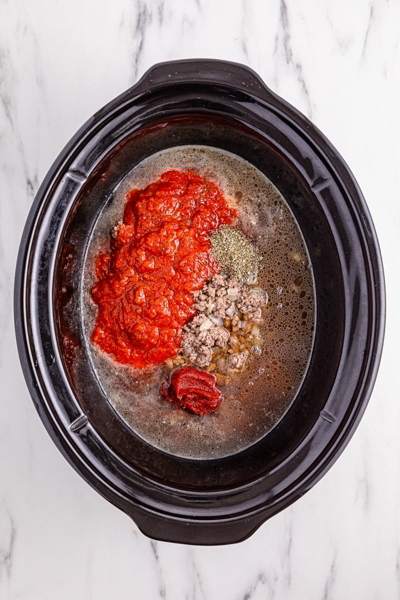 Tomato pasta and beef broth are added to the crockpot.