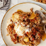 Apple crispy with vanilla ice cream and caramel sauce served on a plate.