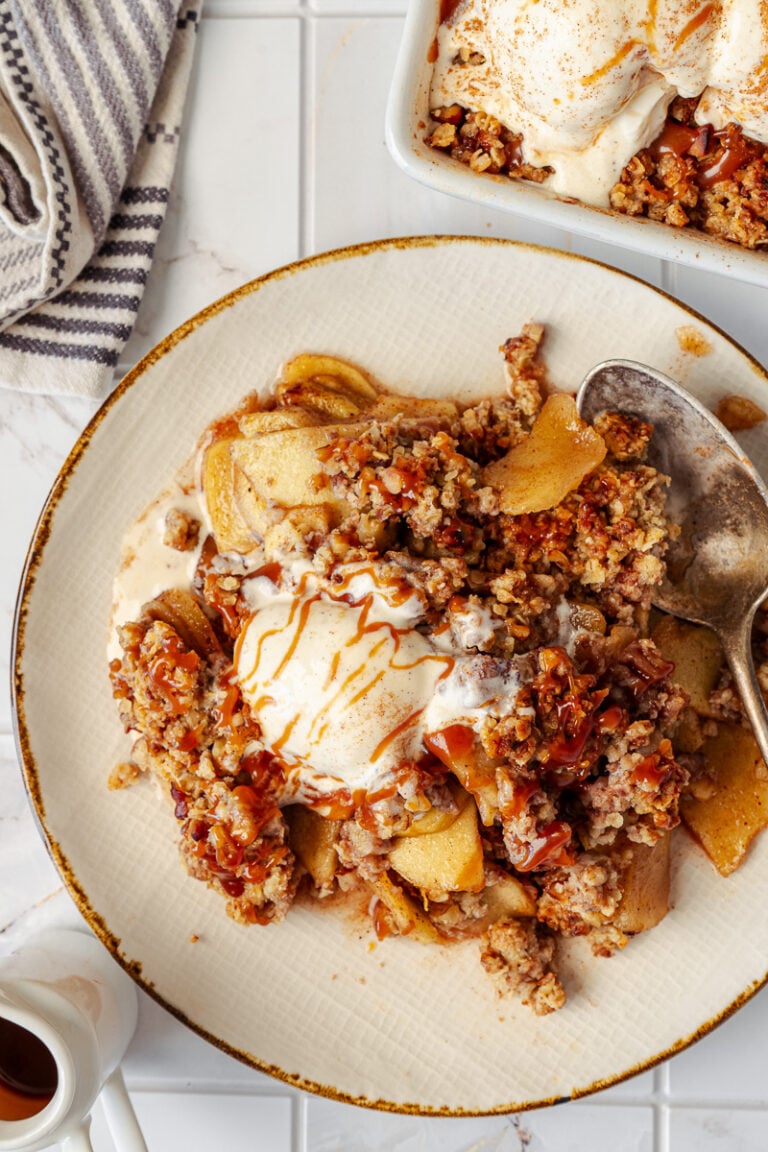 Apple crispy with vanilla ice cream and caramel sauce served on a plate.