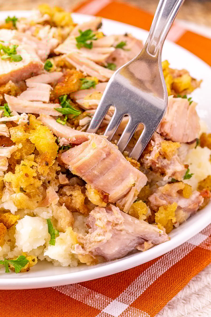 Close up image of crockpot pork chops and stuffing with bite on a fork.