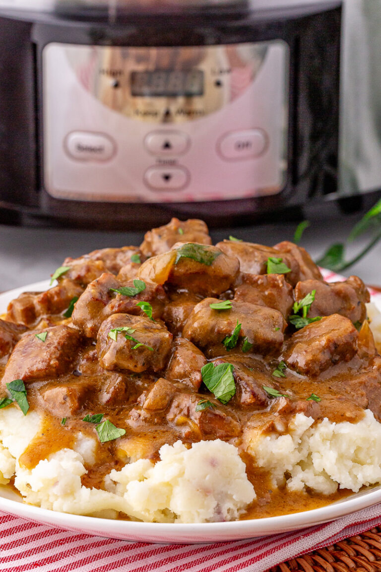 Slow cooker beef tips and gravy served on a bed of mashed potatoes.