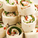 BLT pinwheels stacked on a plate.