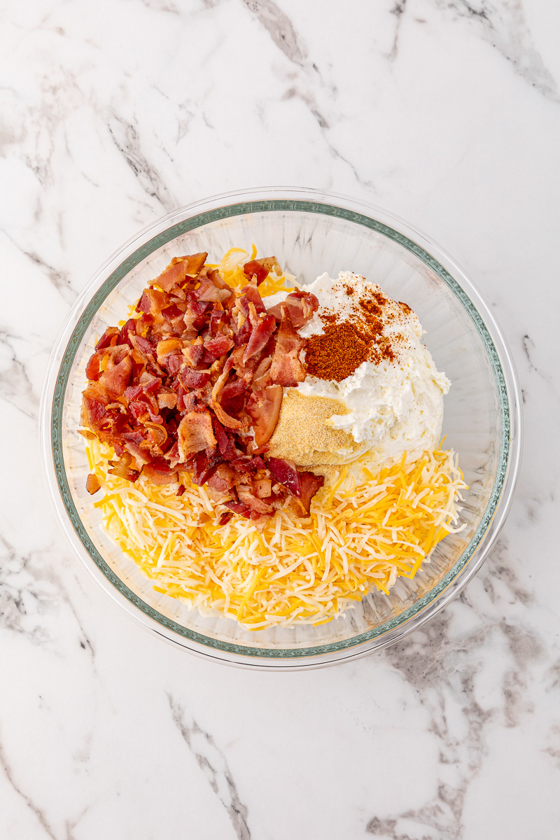 Cream cheese, bacon and shredded cheese in bowl.