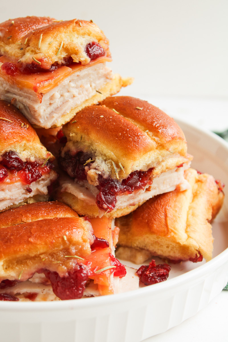 Turkey sliders with cranberry sauce and King's Hawaiian rolls stacked on a plate & ready to serve.