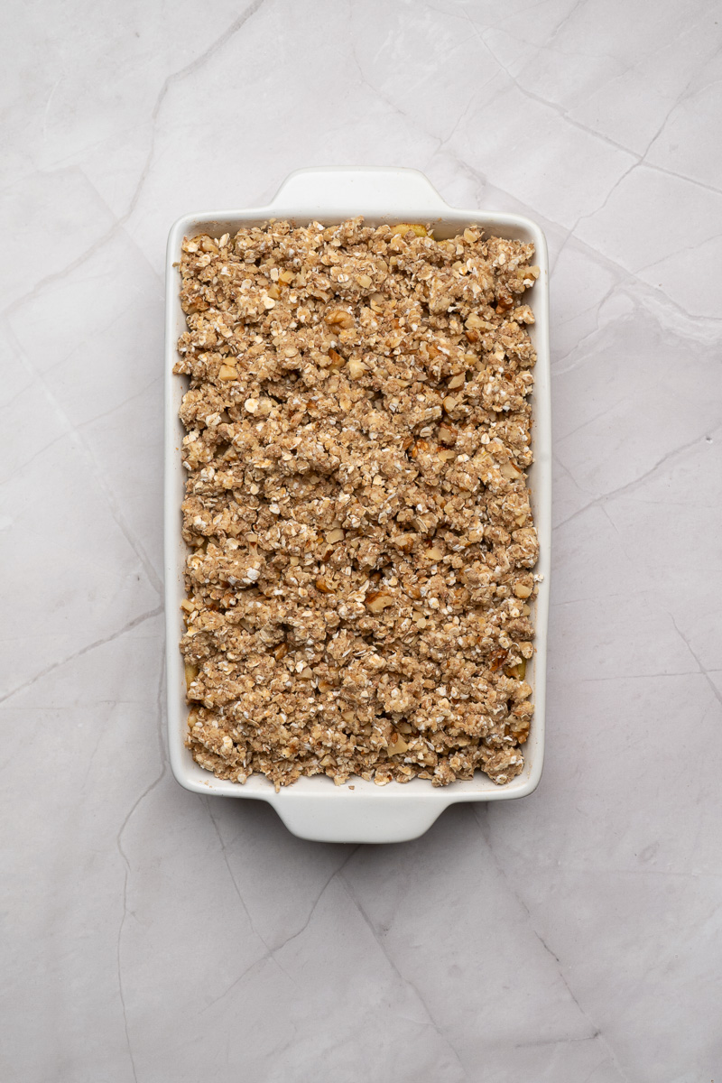 Crumble topping is sprinkled on top of the apple mixture.