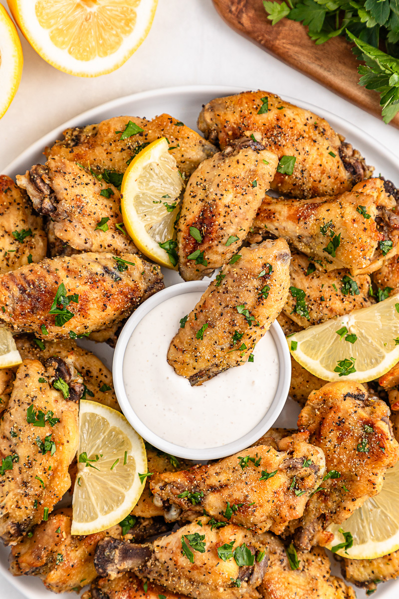Lemon pepper chicken wings served on a plate with dip.