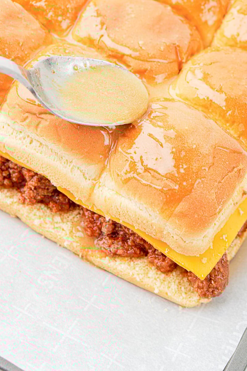 Melted butter is drizzled on top slider buns.