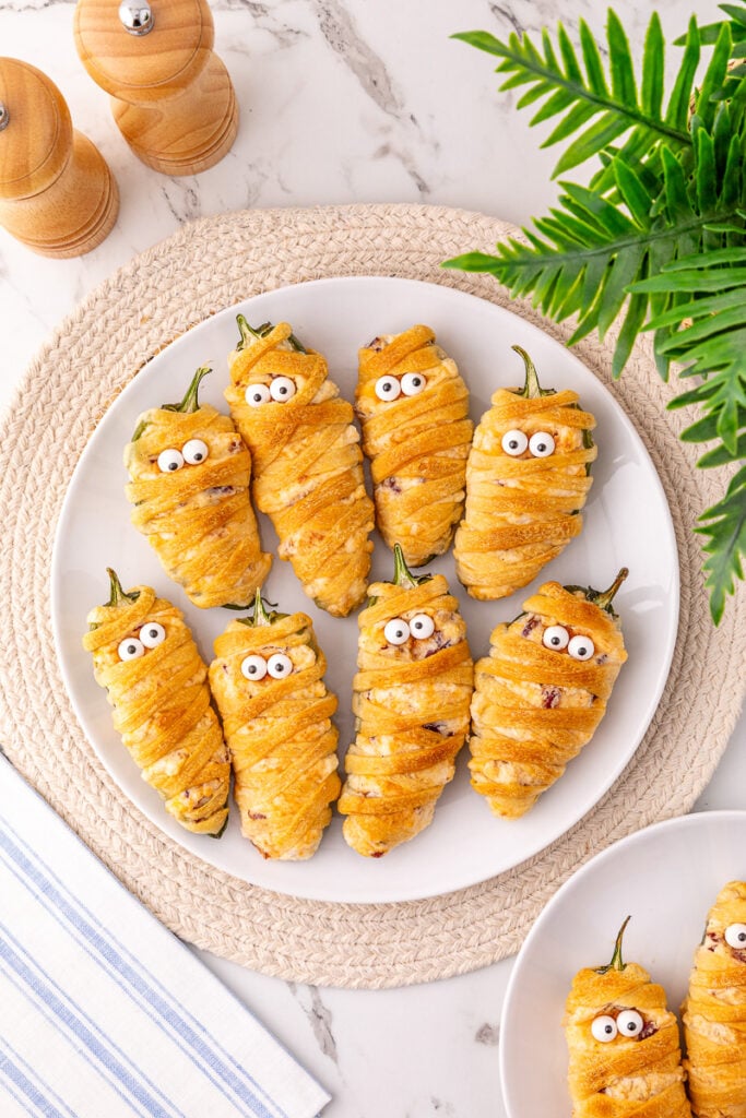 Jalapeno popper mummies on a white plate.