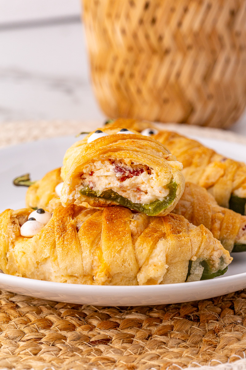 Jalapeno popper mummies with bite removed and placed on a plate.