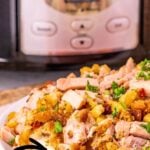 Crockpot pork chops and stuffing served on a plate with mashed potatoes.