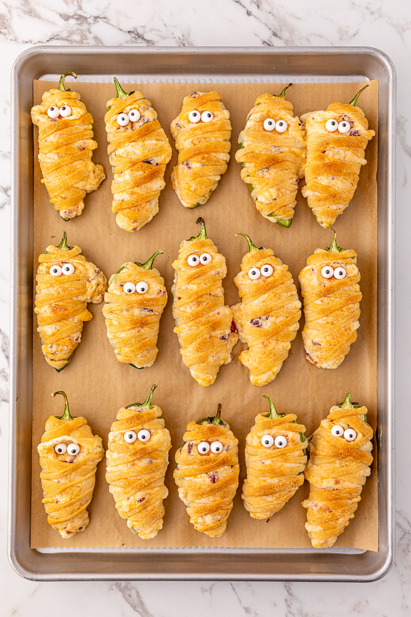 Candy eyeballs are pressed into jalapeno poppers.