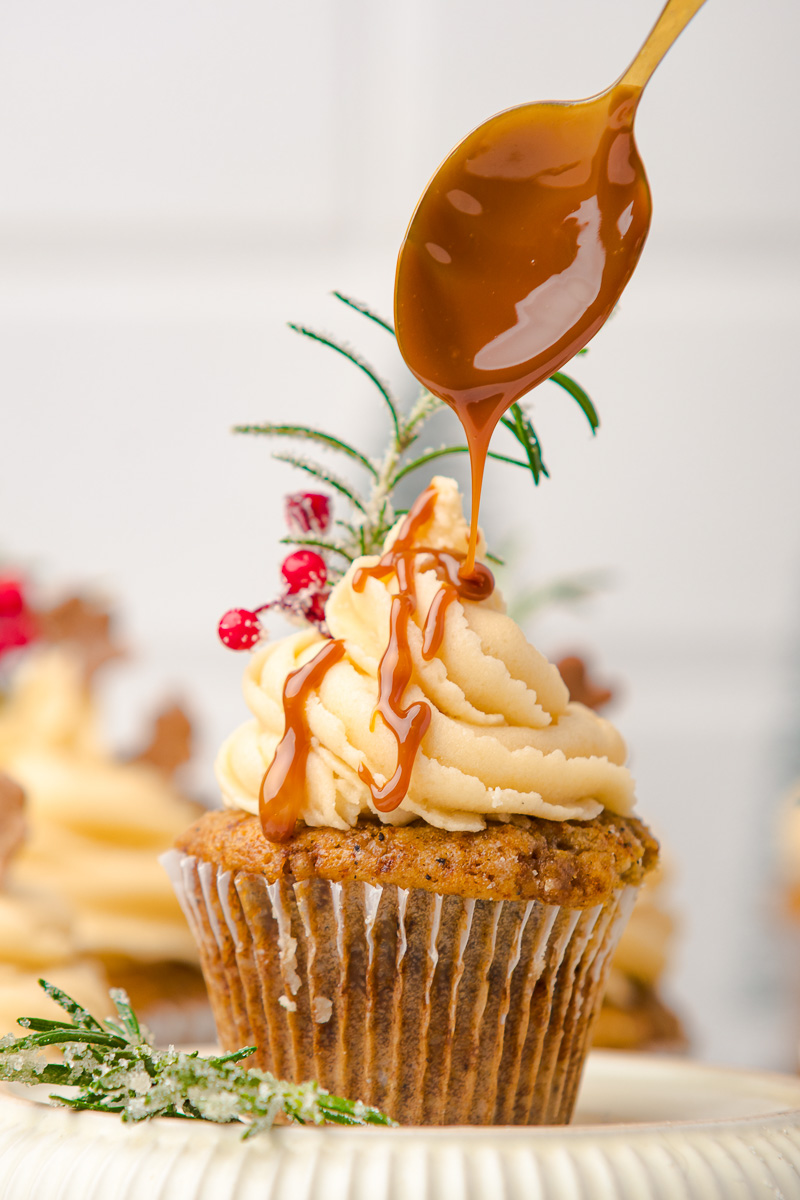 Caramel sauce is drizzled on top of frosted gingerbread cupcake.