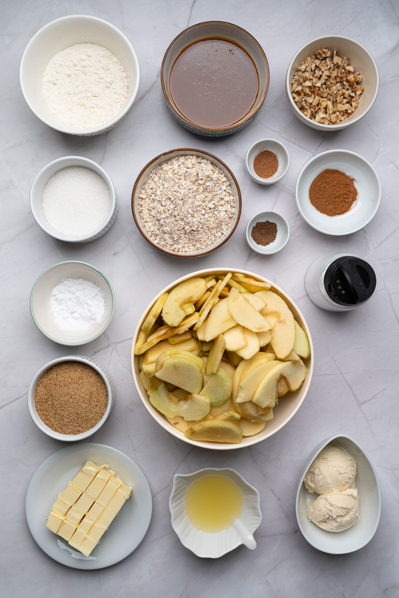 Ingredients for apple crisp in small glass bowls on counter.