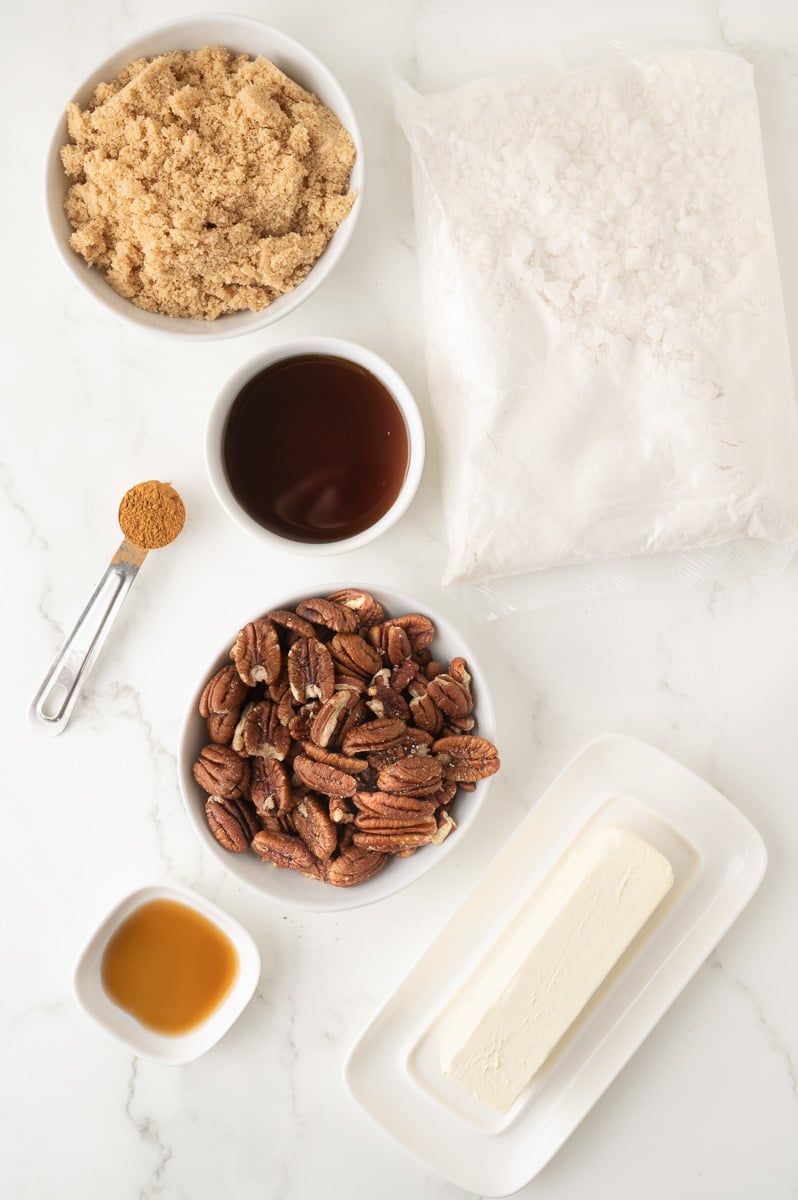 Ingredients for pecan pie dump cake laid out in small bowls on counter.
