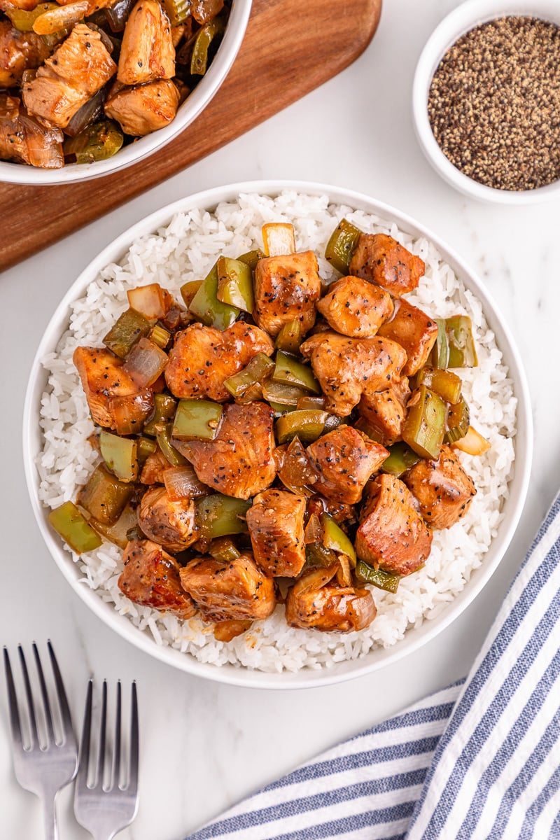 Overhead view of black pepper chicken on a white plate with rice.