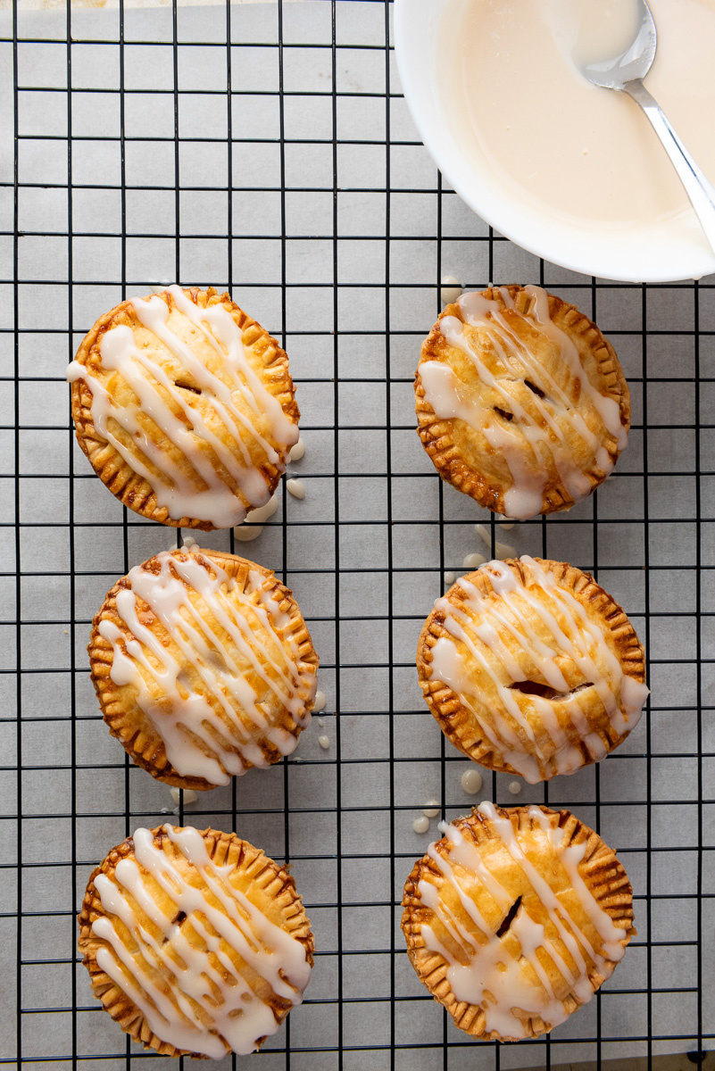Glaze is drizzled on top of apple hand pies.