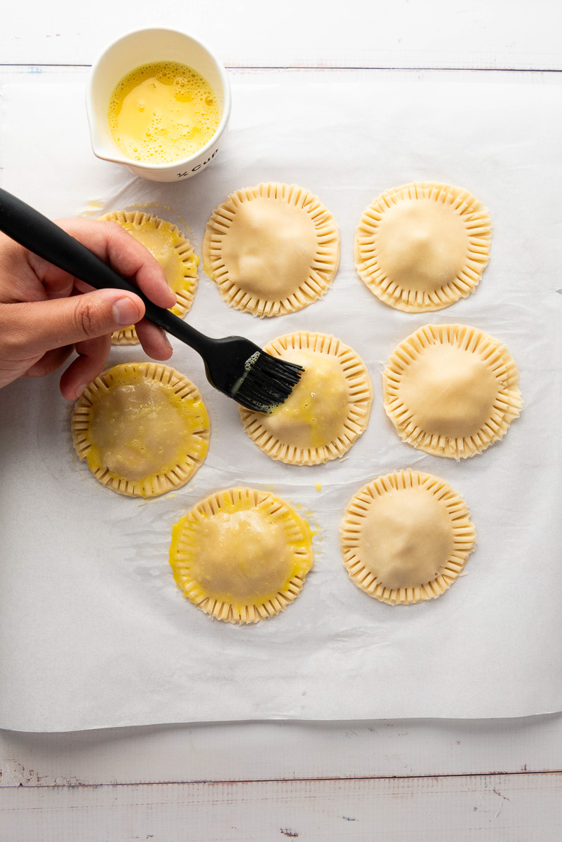 Apple hand pies are brushed with egg wash.