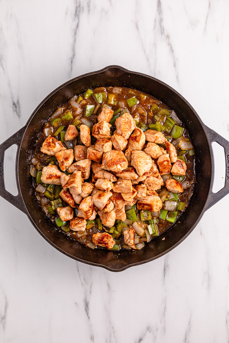 Chicken is adde back to the skillet the onion pepper and celery mixture.