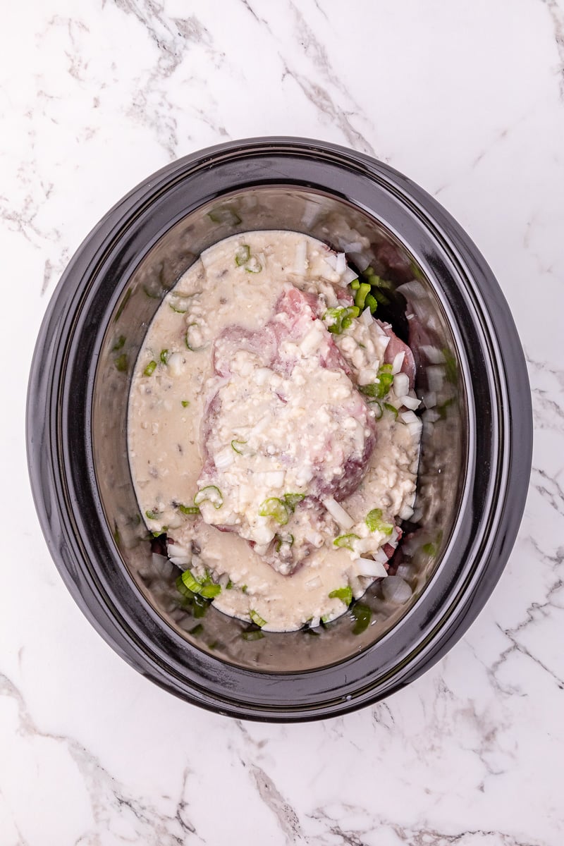 Chicken soup mixture is poured on top of the pork chiops in crockpot.