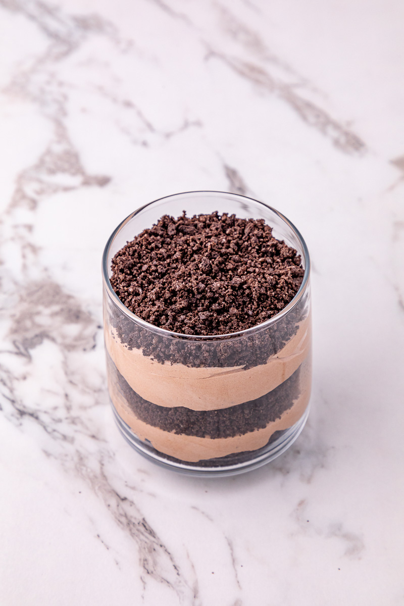 Layered pudding mixture and crushed Oreos in glass.