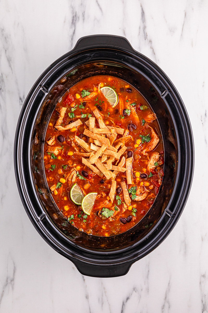 Chicken tortilla soup garnished with sour cream, limes, cheddar cheese and tortilla strips.