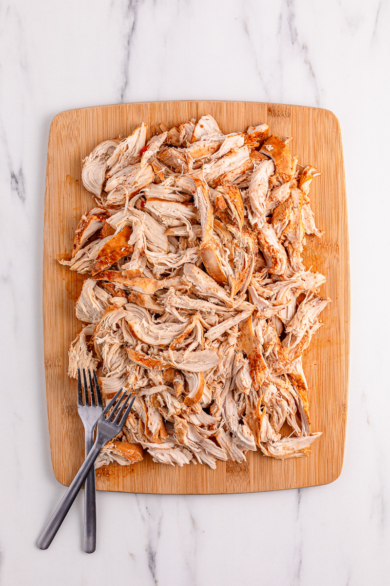 Chicken on wooden cutting board cut into pieces.