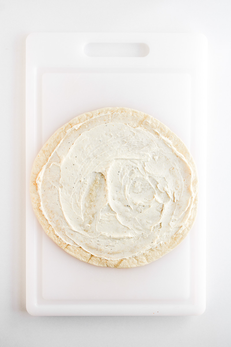 Cream cheese mixture is spread on flour tortilla.
