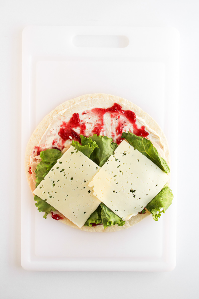 Lettuce and cheese is added to the top of the tortilla.