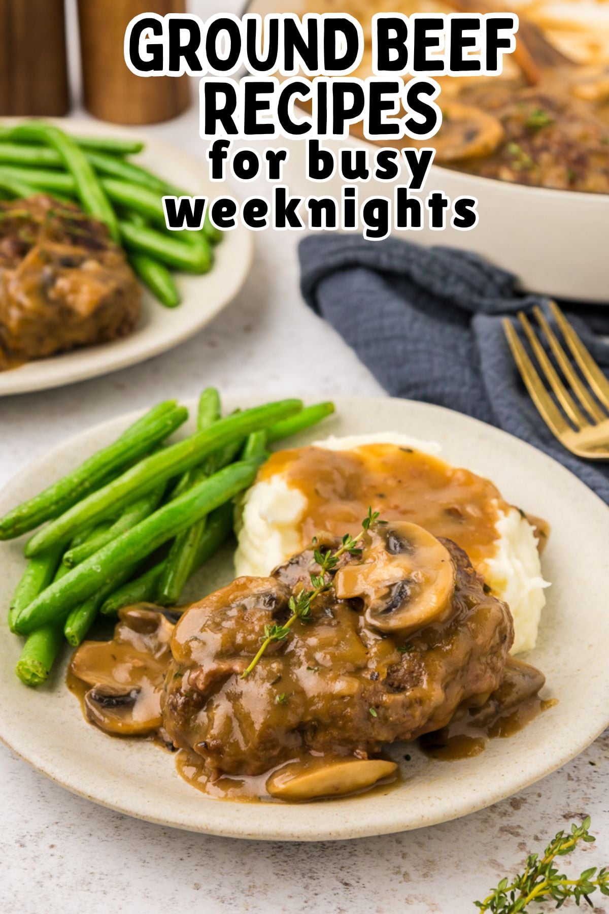 Salisbury steak with gravy served on a plate with mashed potatoes and steamed green beans.