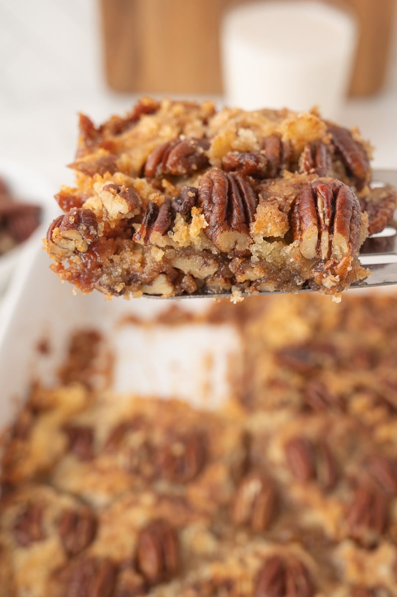 Serving spoon with helping of pecan pie dump cake.