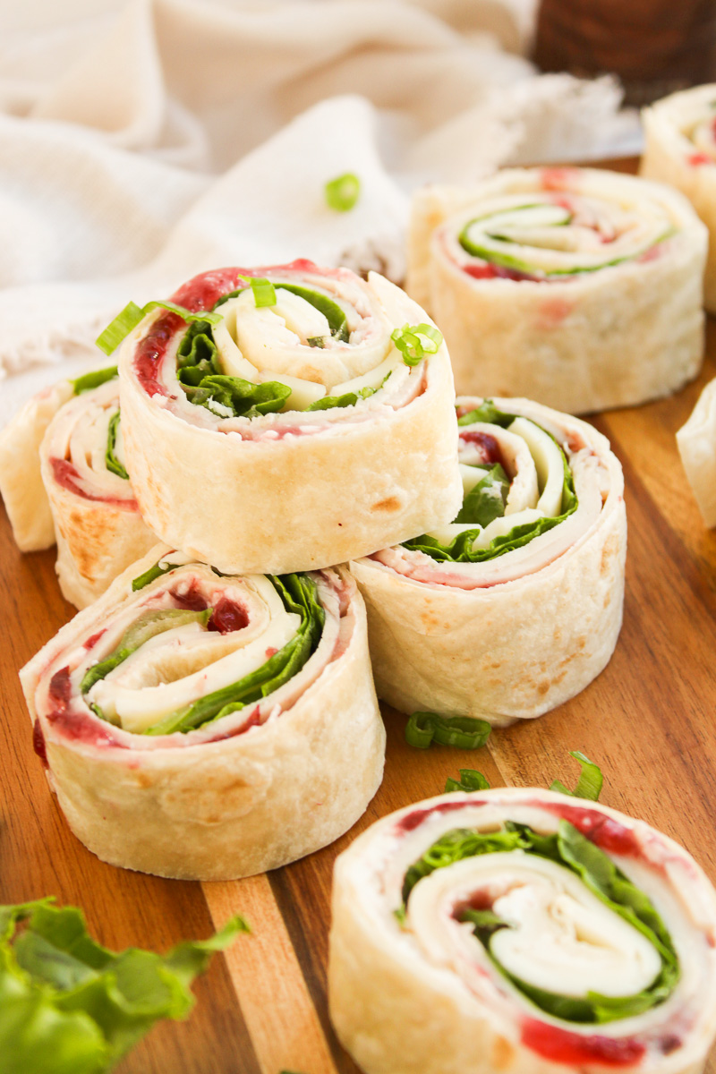 Sliced turkey pinwheels on a wooden board.