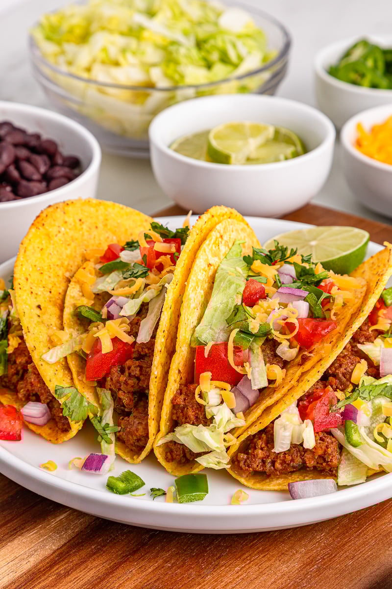Slow cooker taco meat stuffed into tacos with toppings.