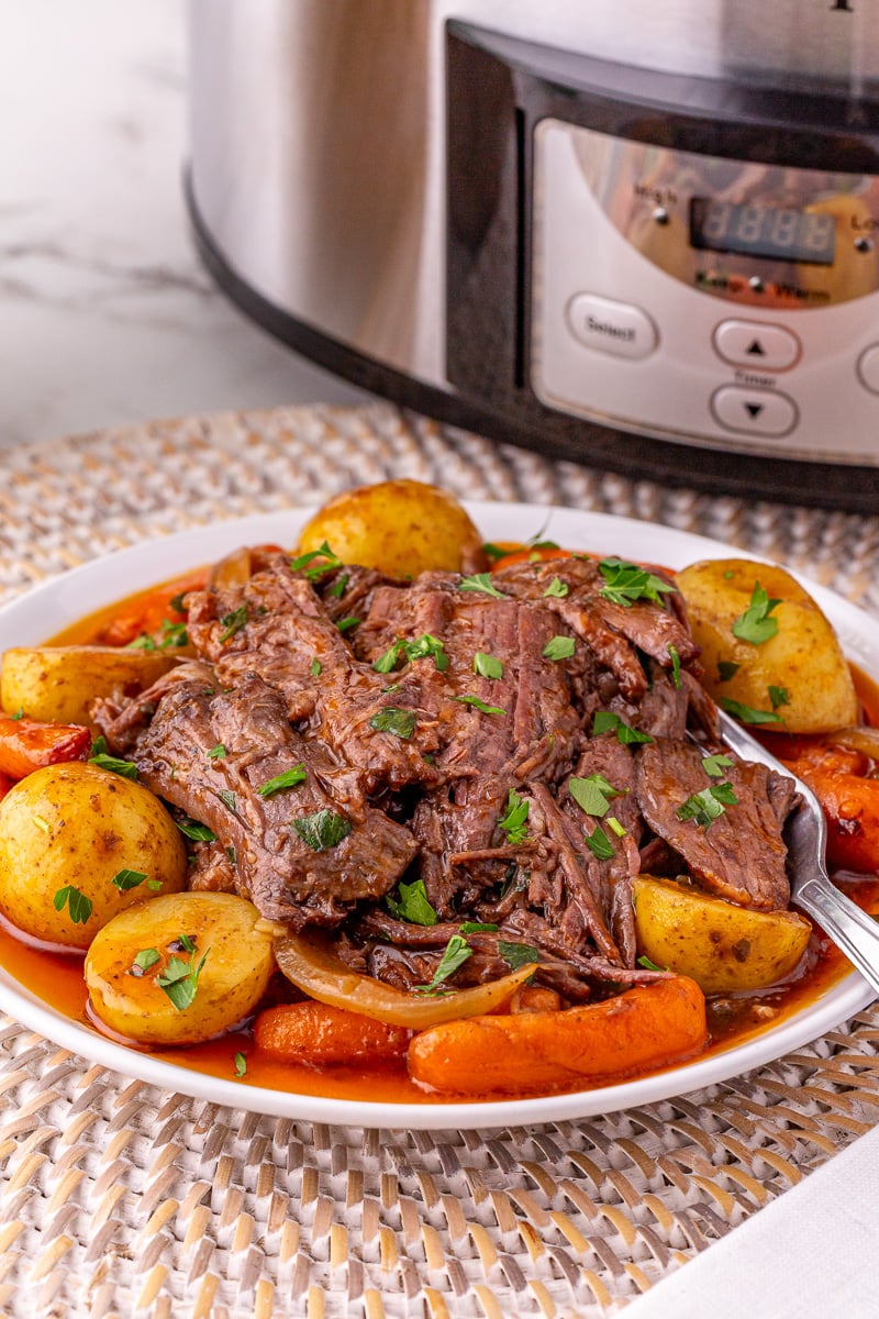 Slow cooker pot roast served on a palte with potatoes and carrots.