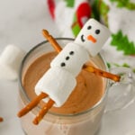 Snowman hot chocolate toppers resting on a cup of hot chocolate.