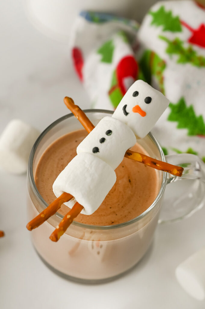 Snowman hot chocolate toppers resting on a cup of hot chocolate.