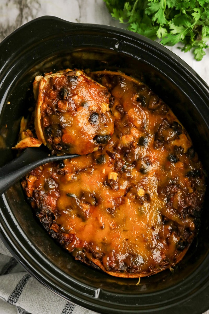 Taco casserole in crockpot scooped up with serving spoon.