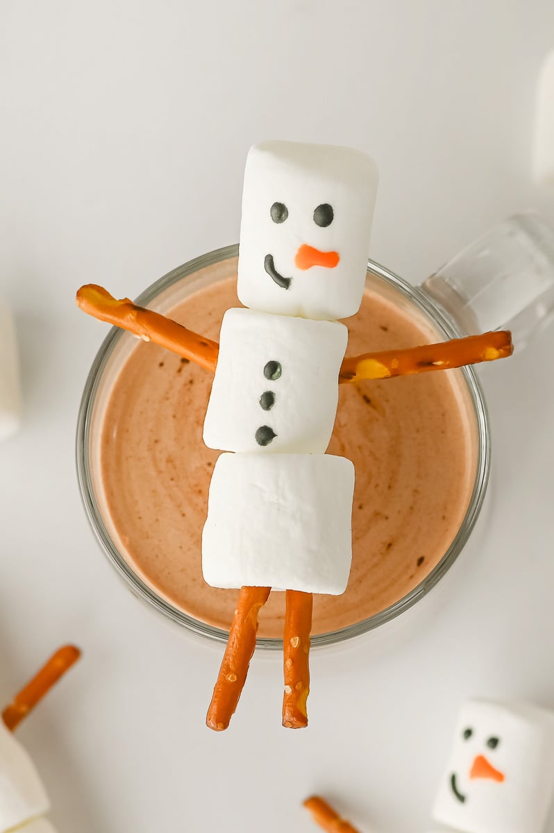 Snowman hot chocolate toppers resting on a mug of hot chocolate.