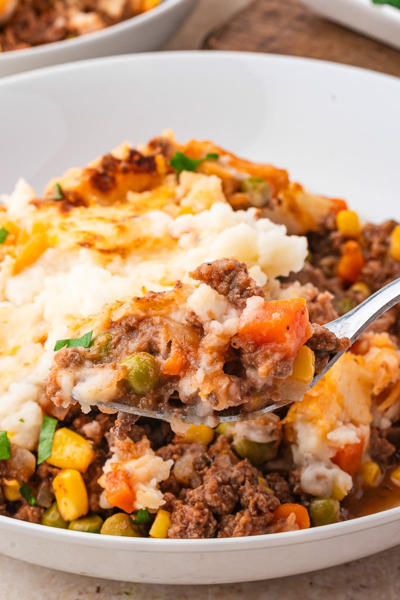 Bite shot of shepherd's pie held over plate.