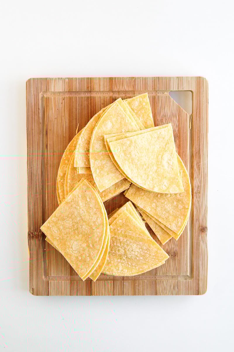Tortillas are cut on wooden board.