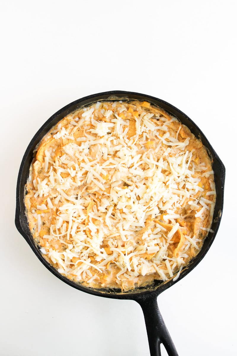 Cheese is sprinkled on top of enchilada skillet and ready to go into the oven.