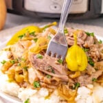 Slow cooker Mississippi pork roast served on a bed of mashed potatoes.