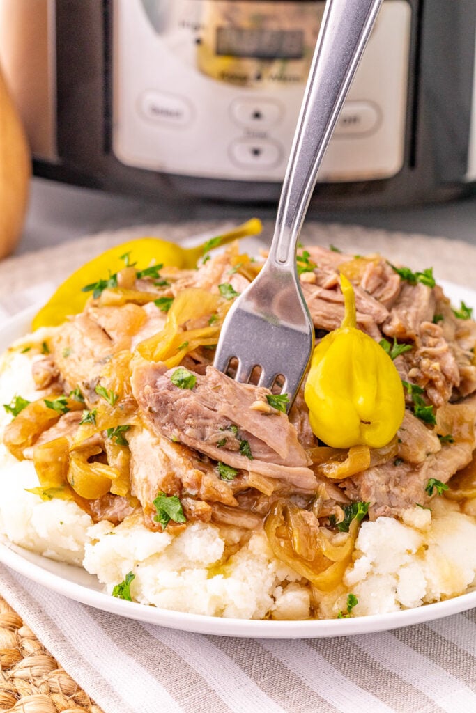 Slow cooker Mississippi pork roast served on a bed of mashed potatoes.