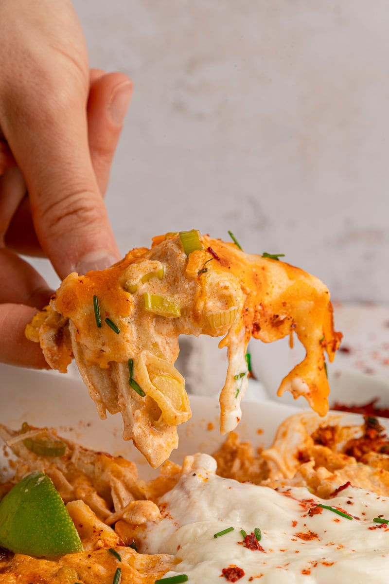 Side view of nacho chip covered in buffalo chickien dip.