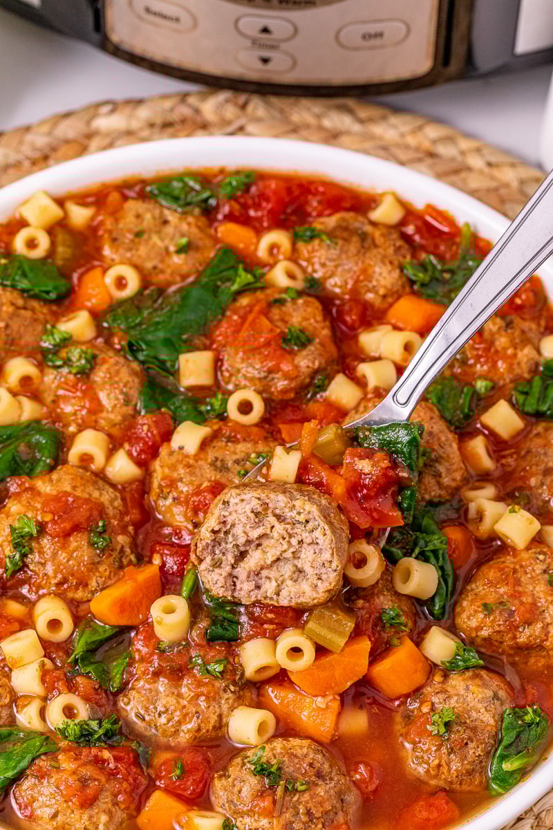 Bite of meatball soup held over bowl of soup.